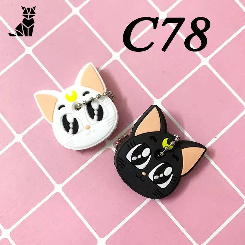 Deux adorables porte-clés en silicone en forme de chat sur un carrelage rose du lot de 2 housses en silicone pour dessins animés